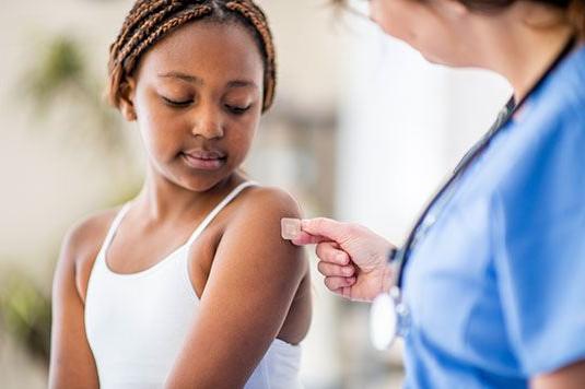 A provider putting a bandage on a girl's arm